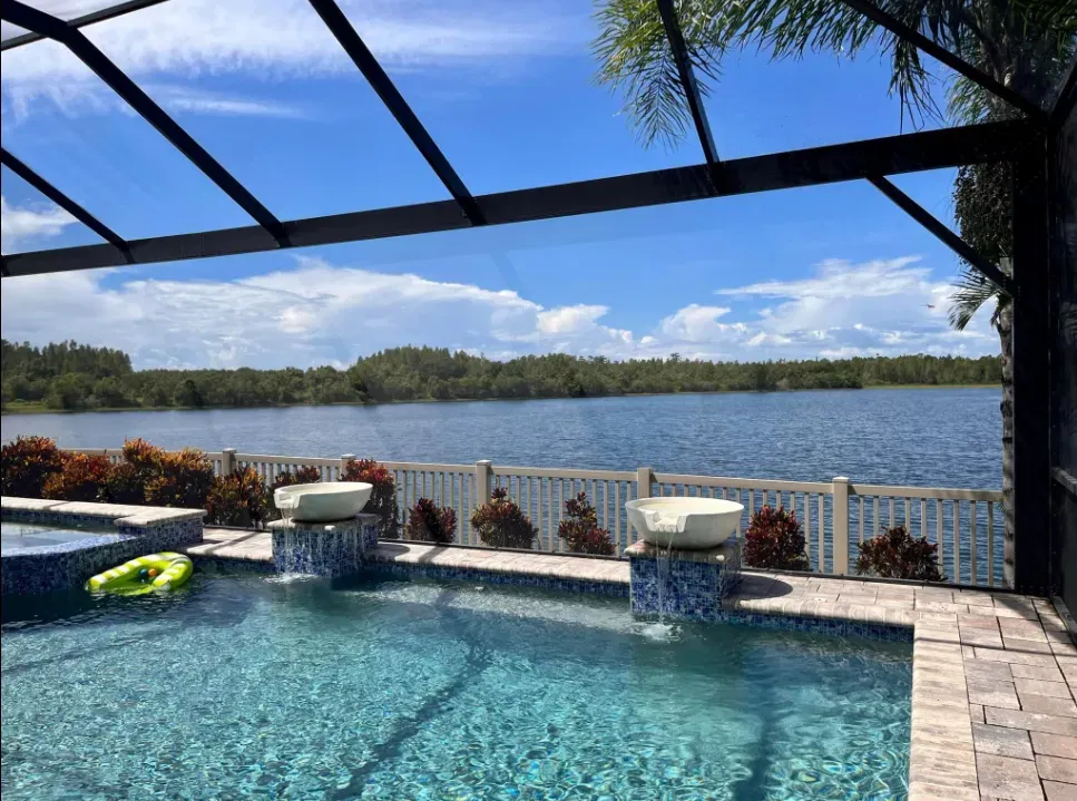 Screened pool enclosure with clear, tightly fitted panels overlooking a lake