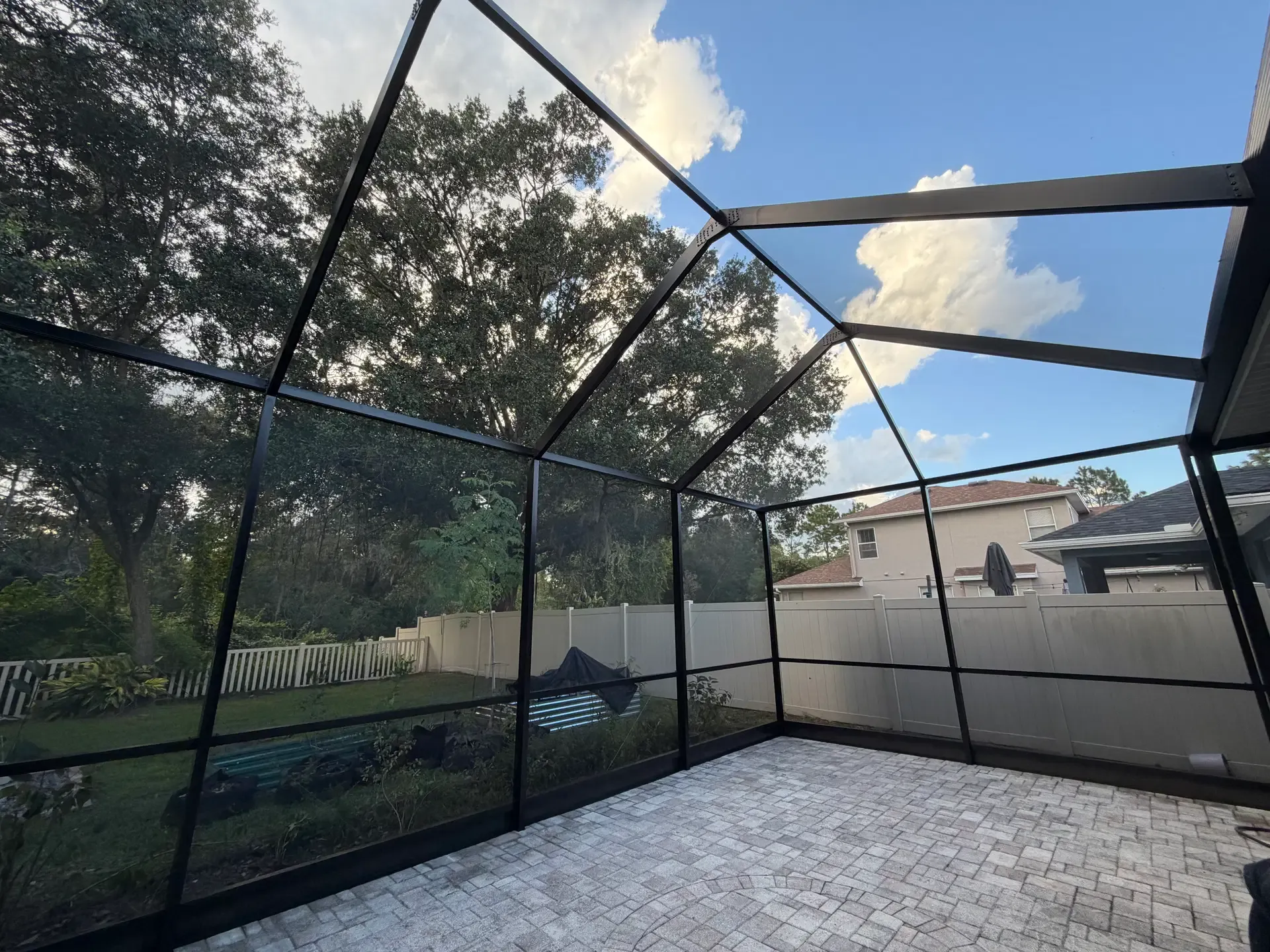 A clean, tightly fitted pool enclosure with dark framing and an open view of the yard