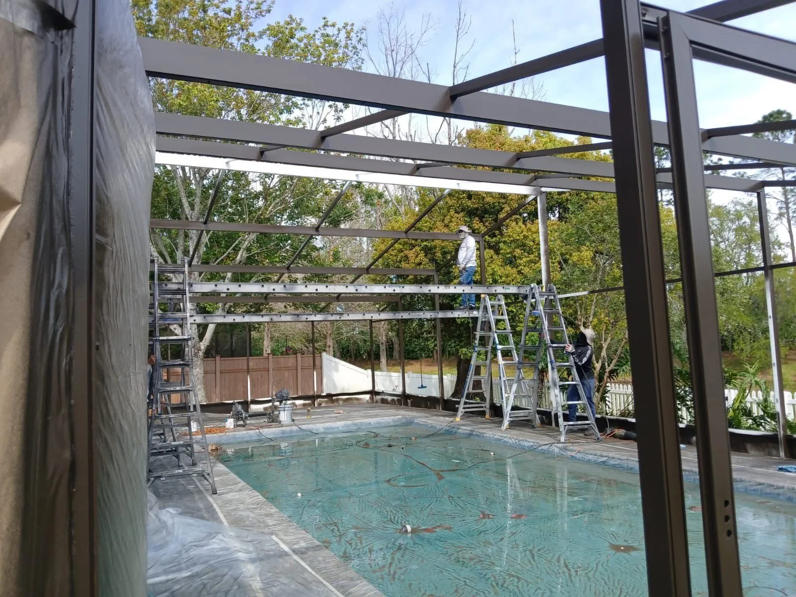 Lily Luxe technicians carefully working on a large pool enclosure rescreening project