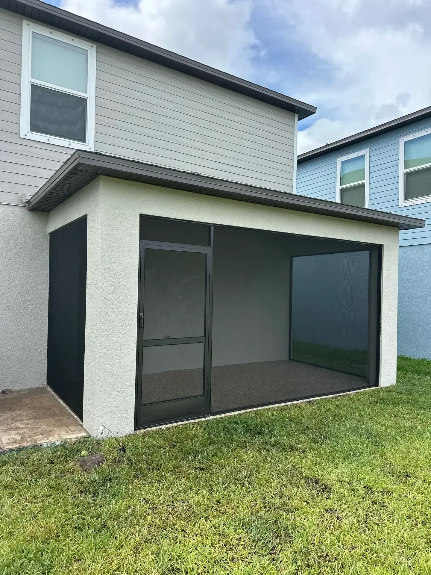New screened patio enclosure attached to a home, with dark frame, screened walls, and a covered roof.